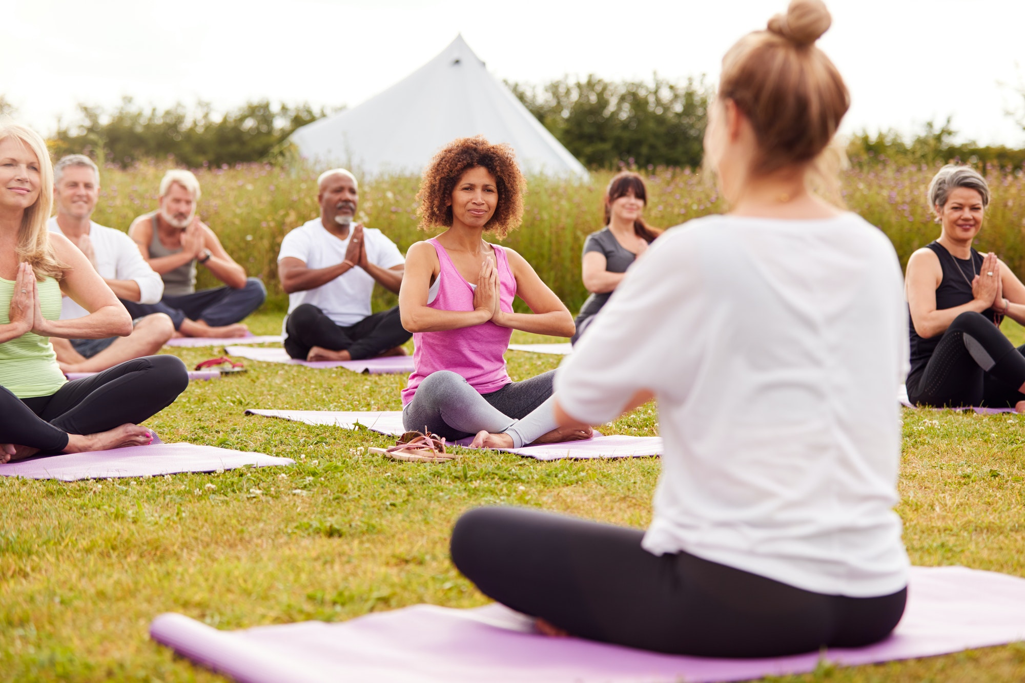 female-teacher-leading-group-of-mature-men-and-women-in-class-at-outdoor-yoga-retreat.jpg