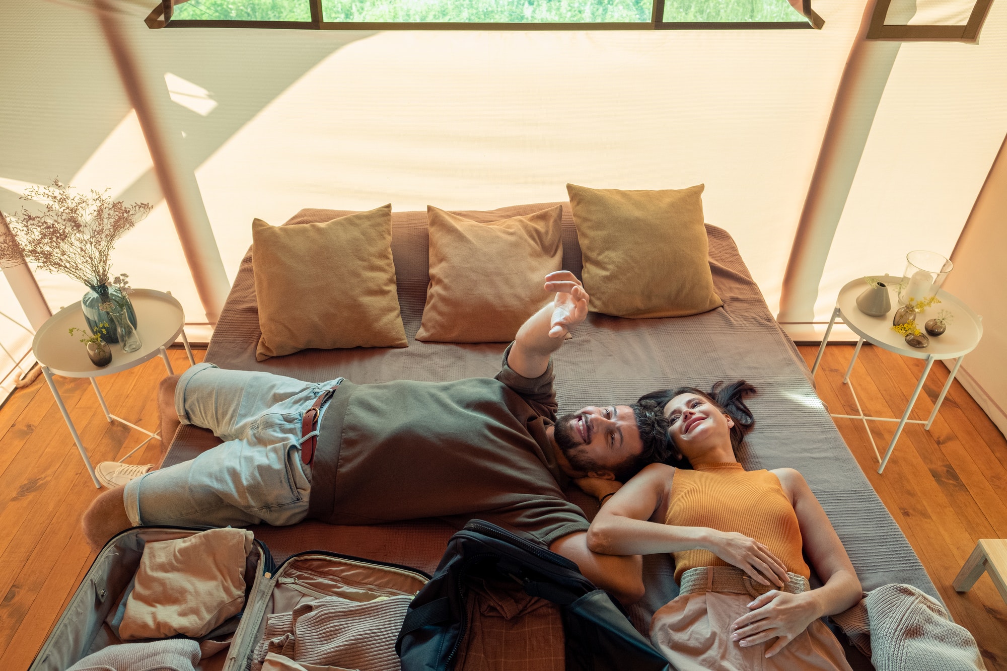 happy-idyllic-couple-relaxing-on-large-bed-in-glamping-house.jpg